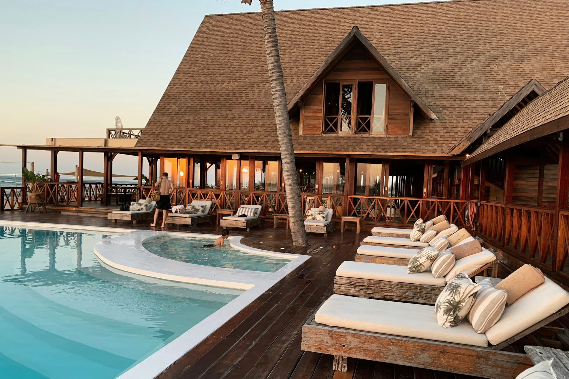 Luxury resort swimming pool and palm trees at dusk with warm lighting